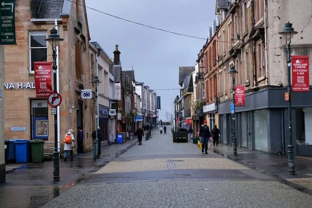 Fort William's pedestrianised High Street on a wet day, with Highland Cinema banners on the lamp posts
