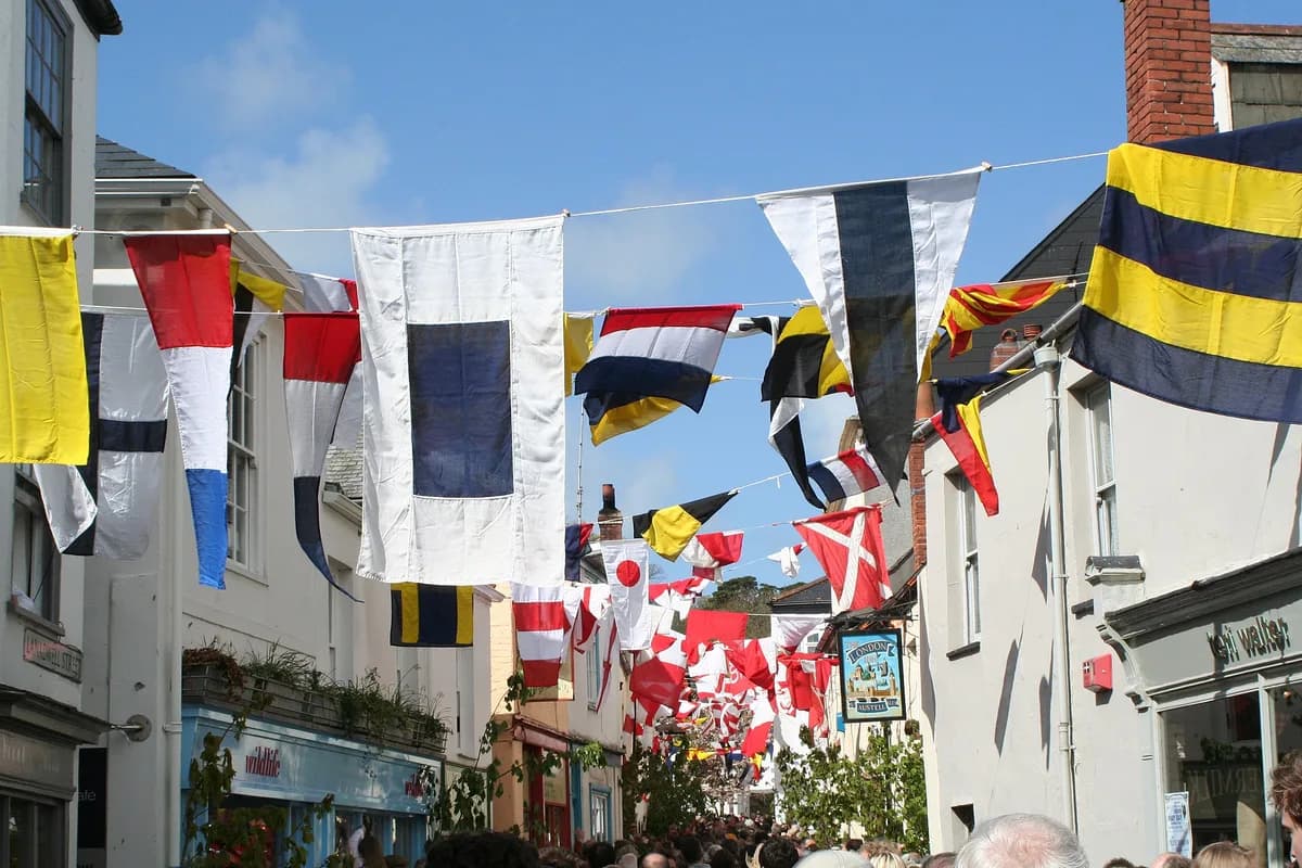 Flags strung across Lanadwell Street on May Day, with the London Inn pub sign and the crowd at the bottom of the street
