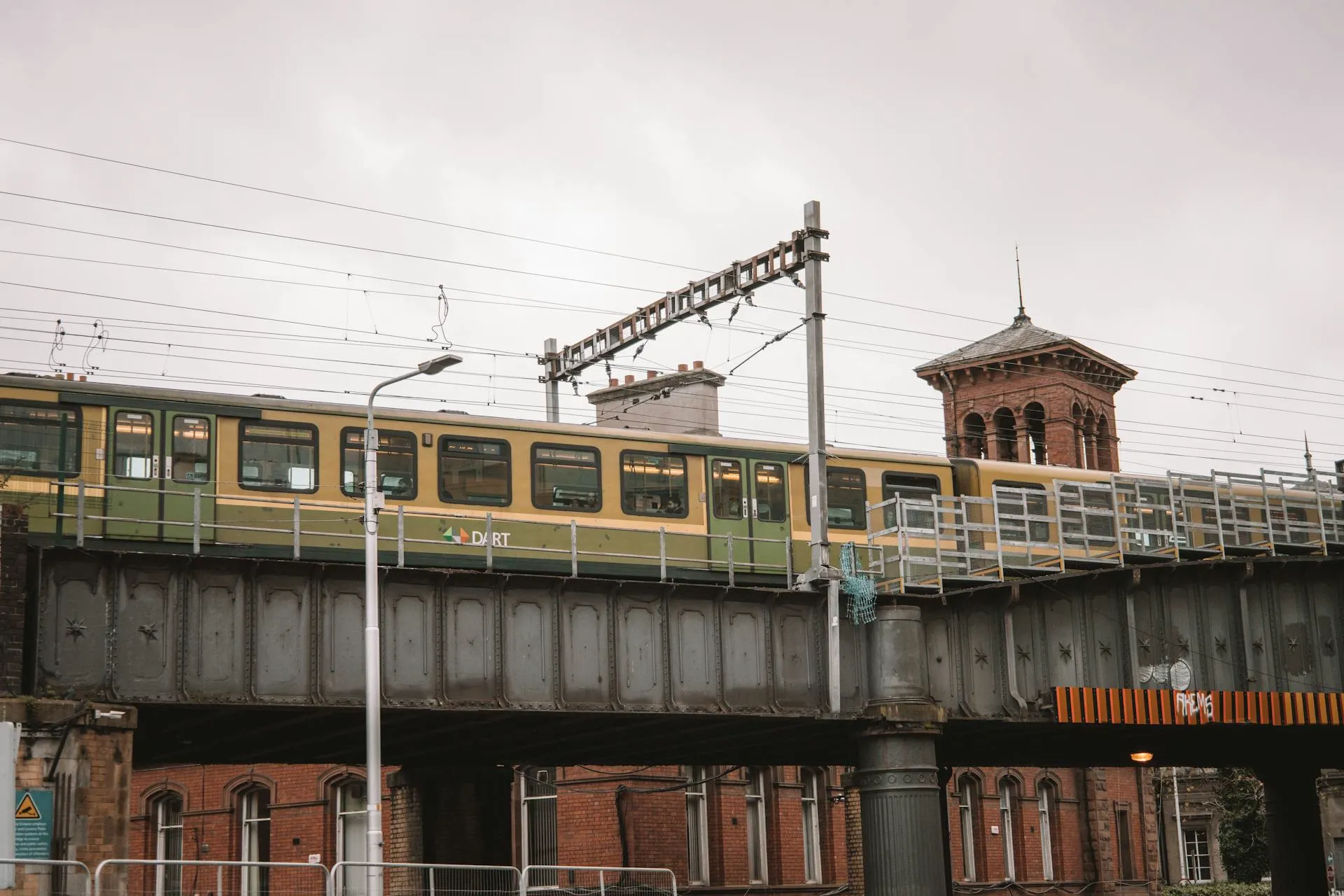 A DART commuter train crossing a red-brick railway bridge in Dublin
